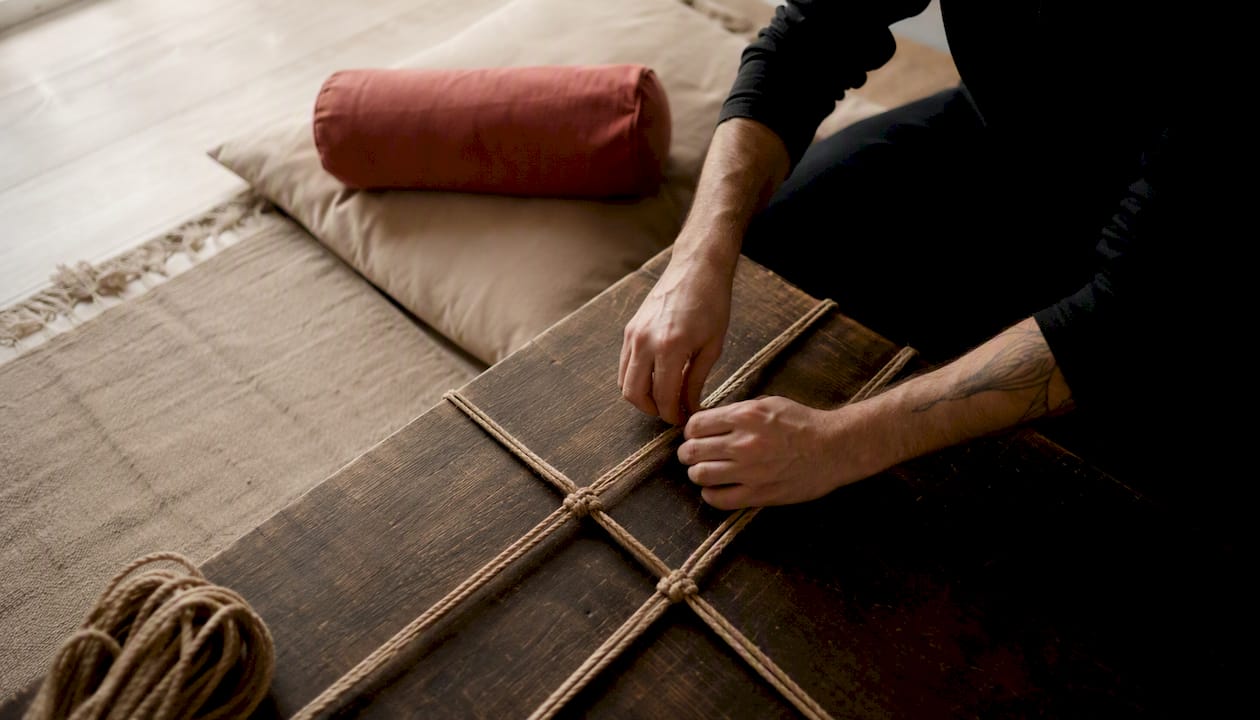 Gros plan sur des mains réalisant des nœuds basiques de shibari sur une plateforme