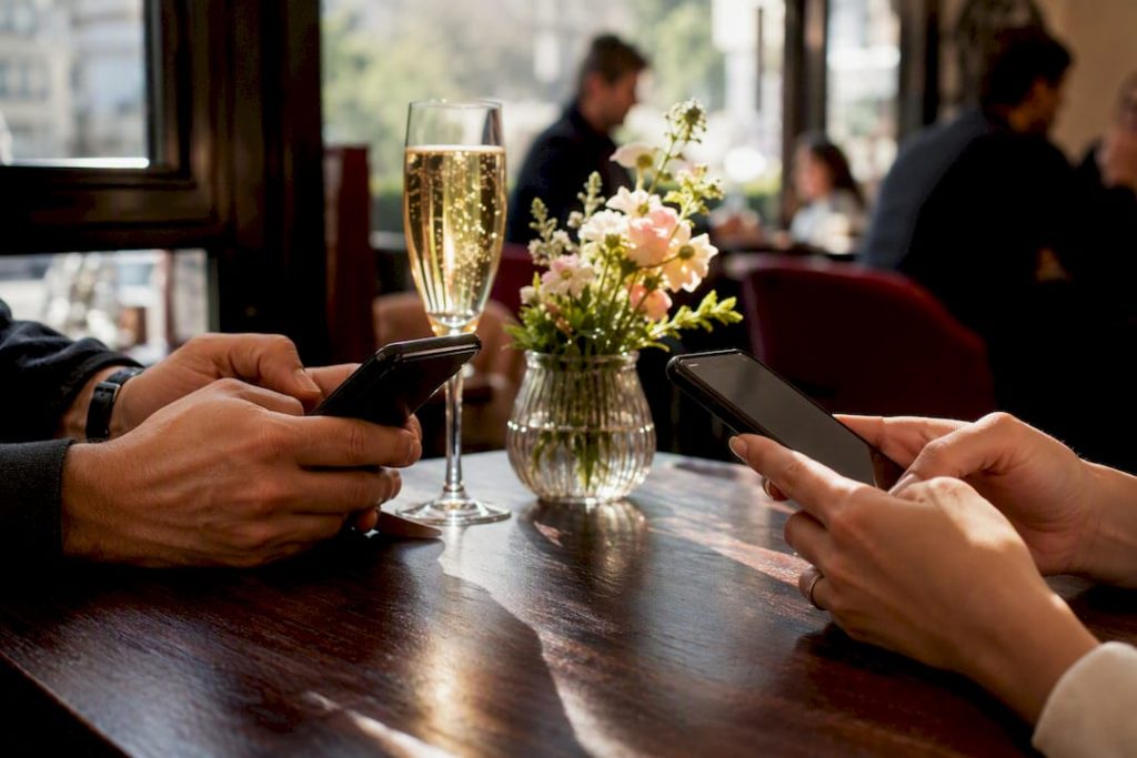 Mains tapant sur des smartphones à une table de café